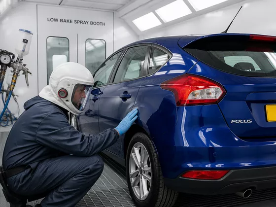 Professional UK car bodyshop spray booth featuring clean paint equipment and automotive panel inspection