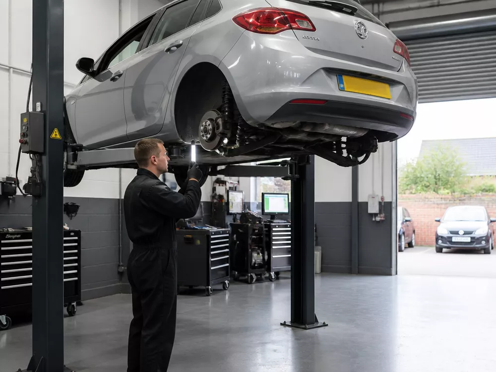 Independent automotive workshop bay in Greater Manchester with car on hydraulic lift for inspection and repairs